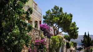 A street with stone walls, a balcony, and purple flowers. - Sunny Palace Studio 2 (Dubrovnik)