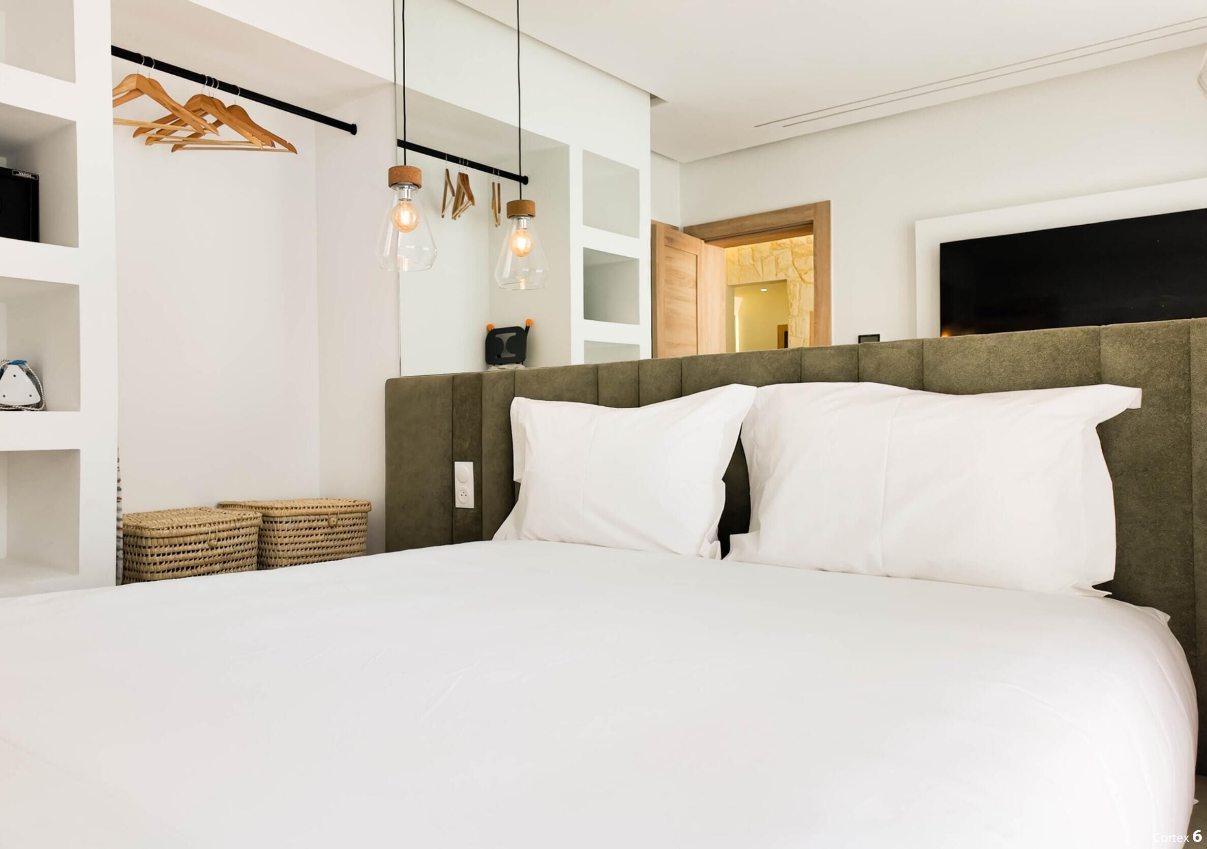A modern bedroom with a large bed, wooden shelves, and a television on the wall.