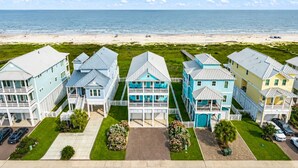 A coastal residential area with houses, a beach, and a clear sky.