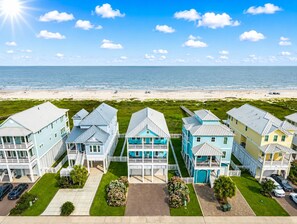 A coastal residential area with houses, a beach, and a clear sky. - Beachfront | First Row Views | Sleeps 16 | Hot Tub (Galveston)