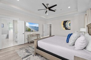 Een slaapkamer met een bed, een plafondventilator, een televisie en een schilderij aan de muur.