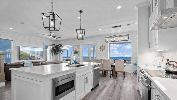 A modern kitchen with a large island, white cabinetry, and a view of the ocean.
