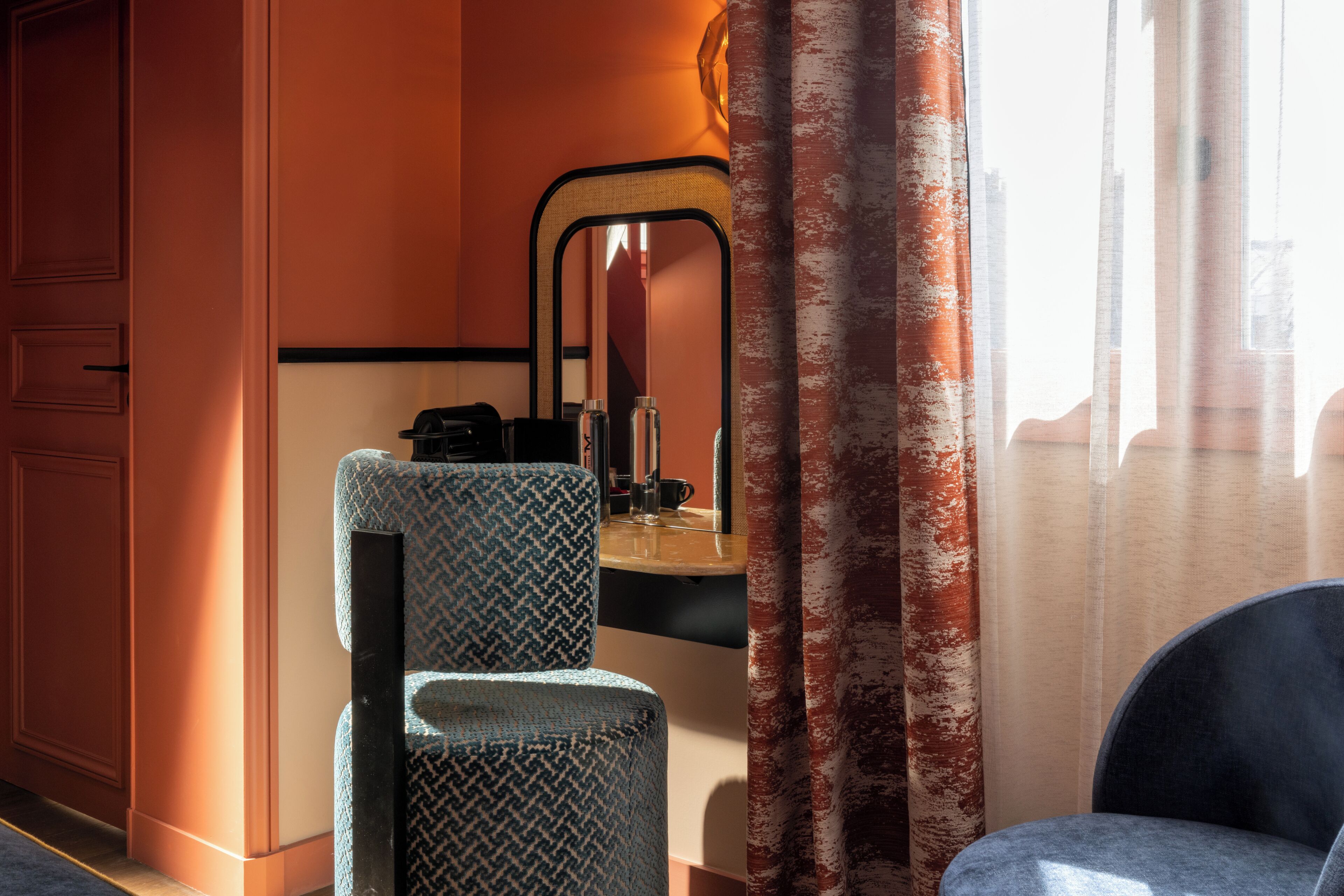 A room with a herringbone-patterned chair, a mirror, and a wooden counter.