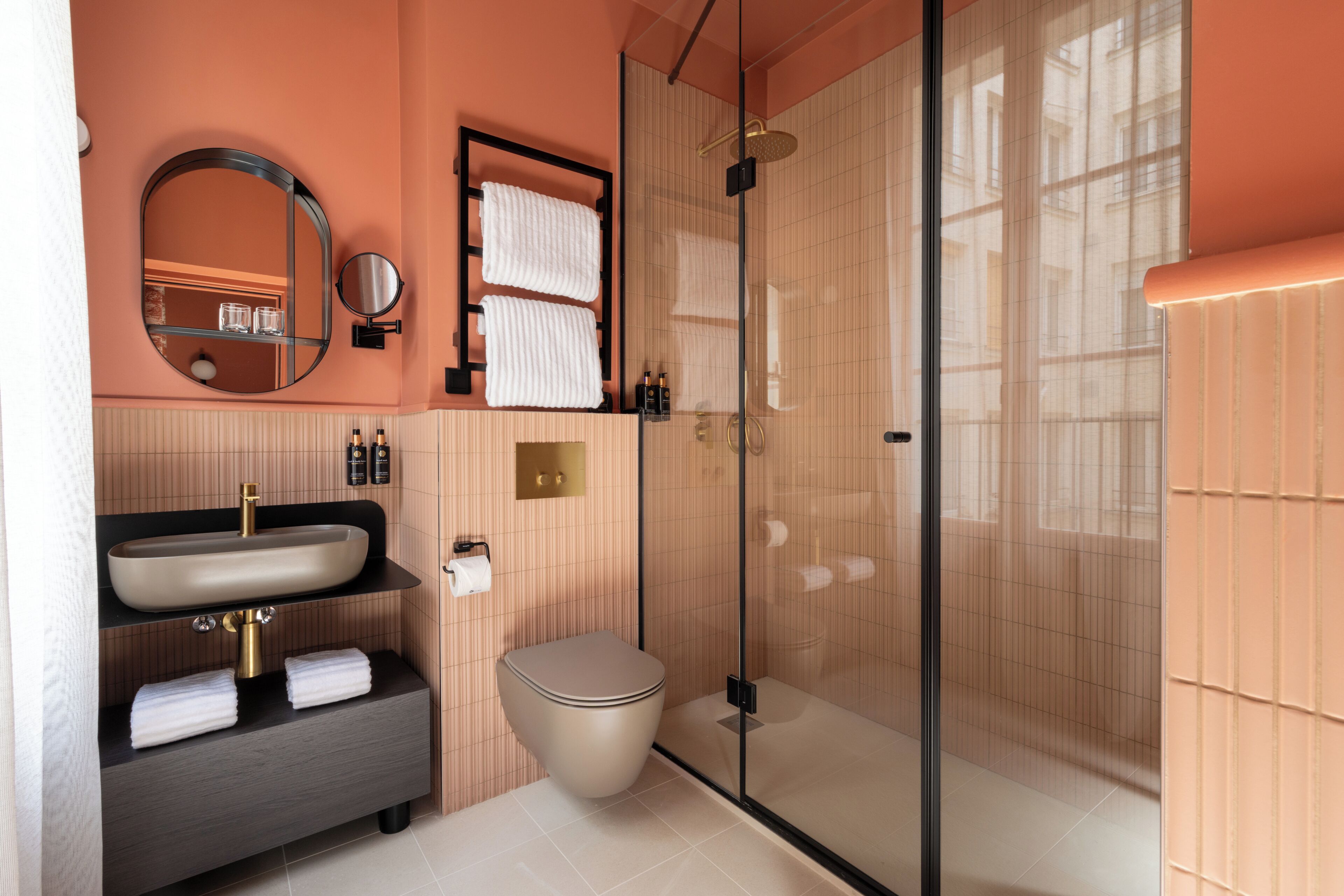 Une salle de bain moderne avec une douche à parois de verre, un lavabo doté d’un robinet doré et des toilettes.
