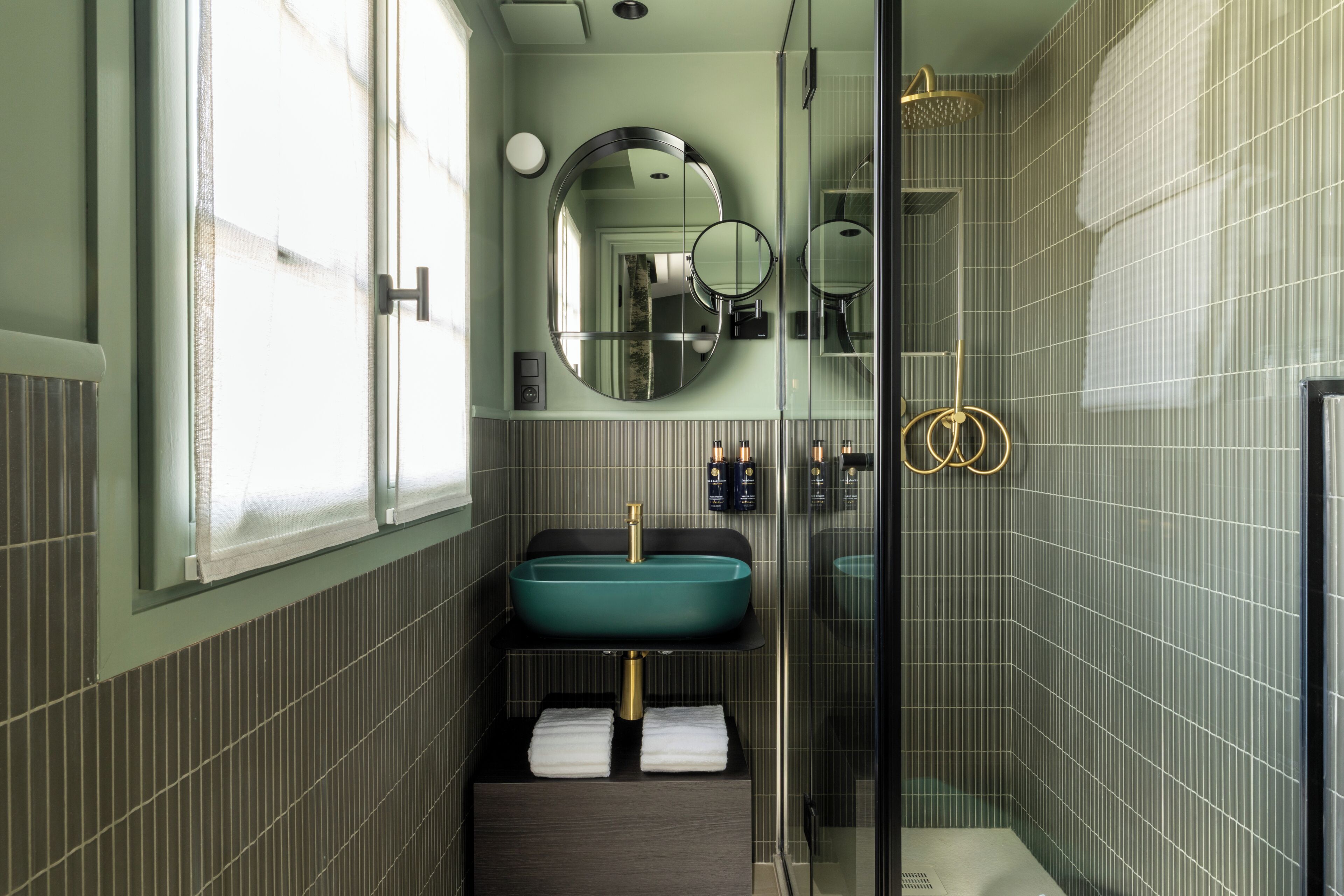 A bathroom with a large mirror, a sink, and a shower.