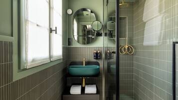 A bathroom with a large mirror, a sink, and a shower.