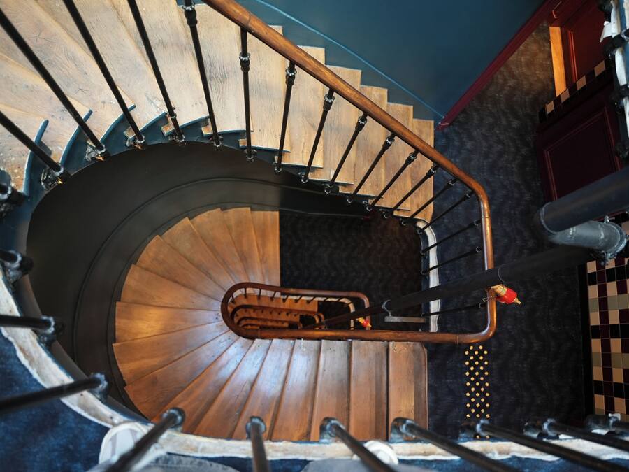 A spiral staircase with a wooden finish and metal railings.