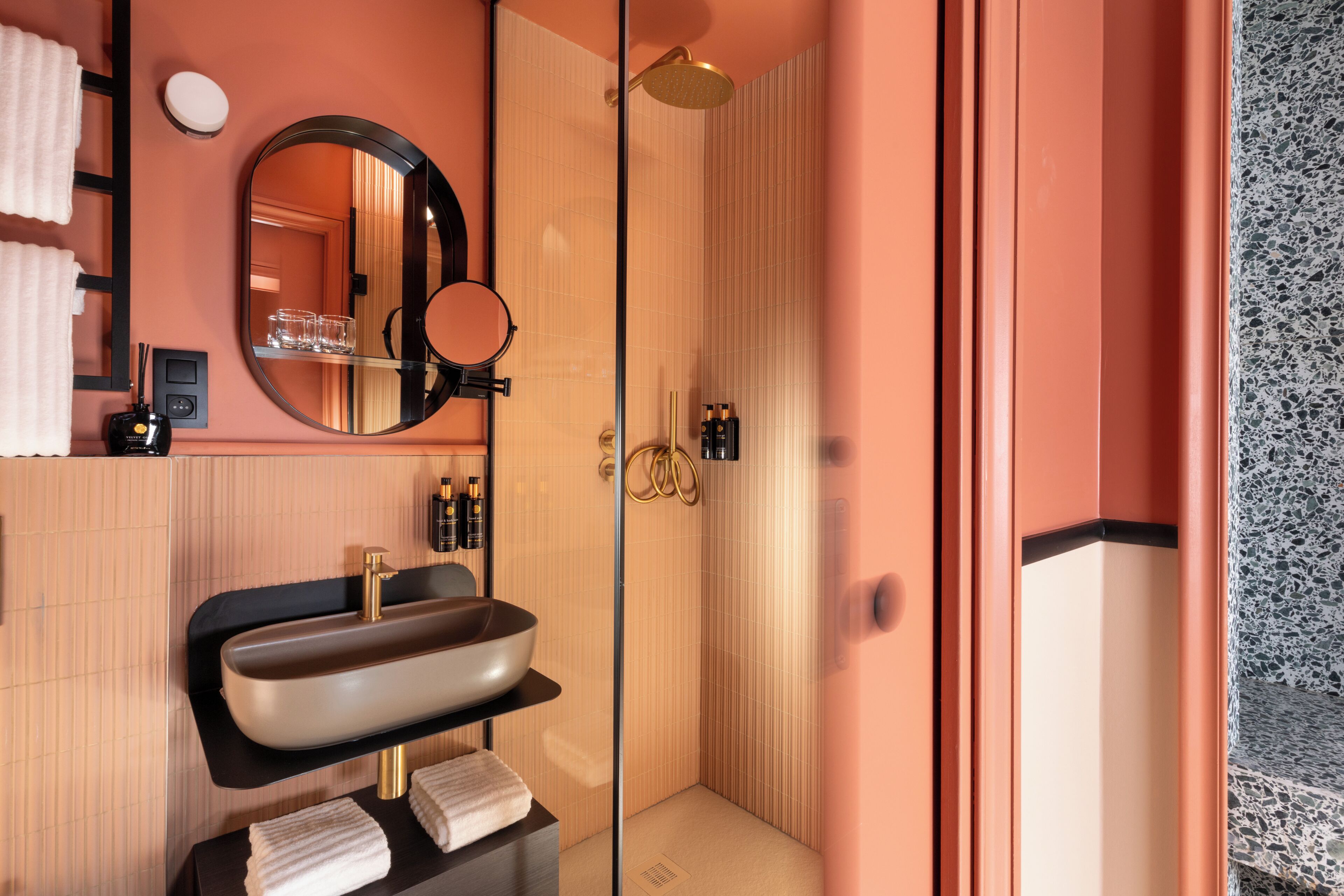 Ein modernes Badezimmer mit einem großen Spiegel, einem Waschbecken mit Schüsselbecken, einer Dusche mit Glastür und einem Handtuchhalter.