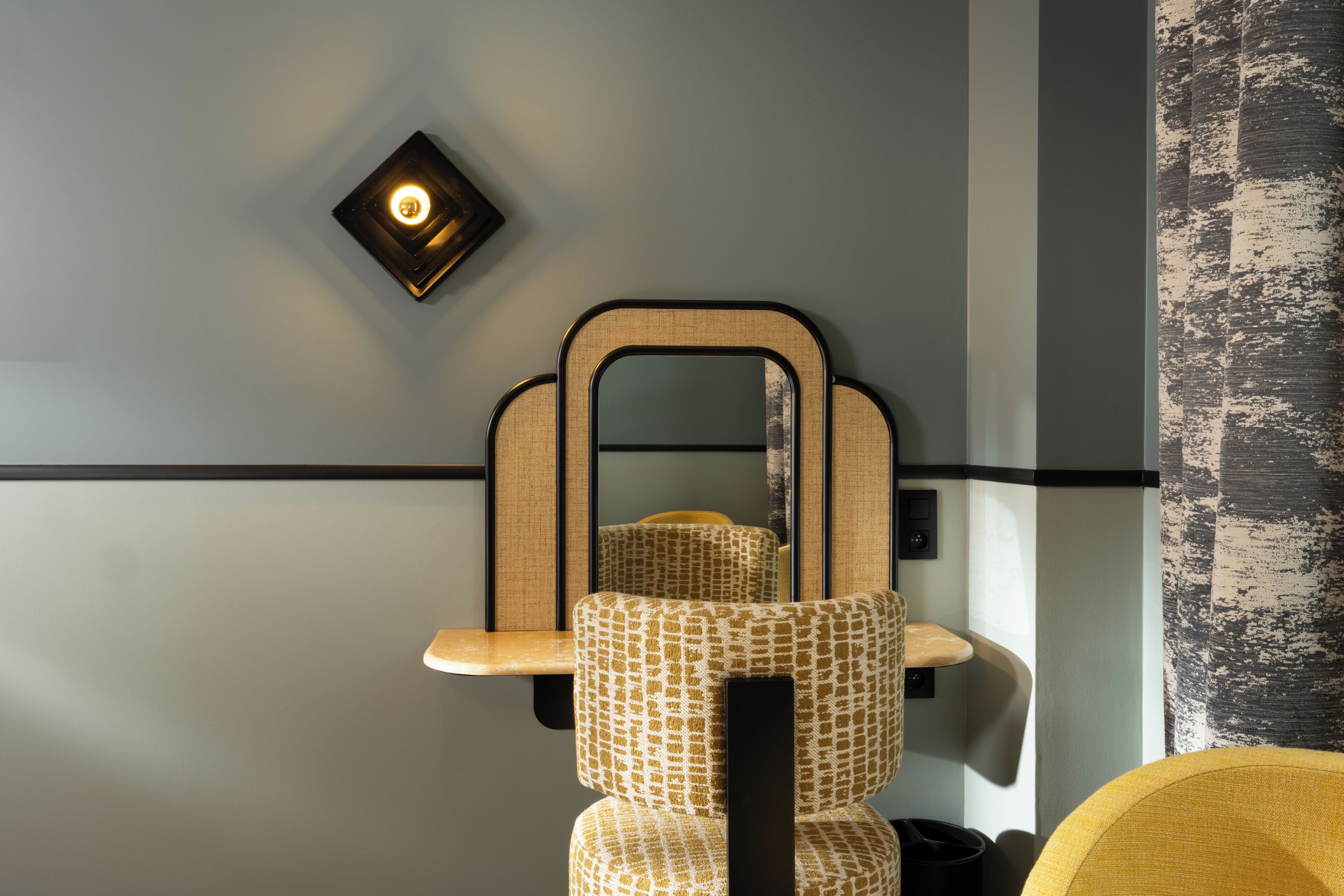 A modern room with a wall-mounted mirror, a light fixture, and a patterned chair.