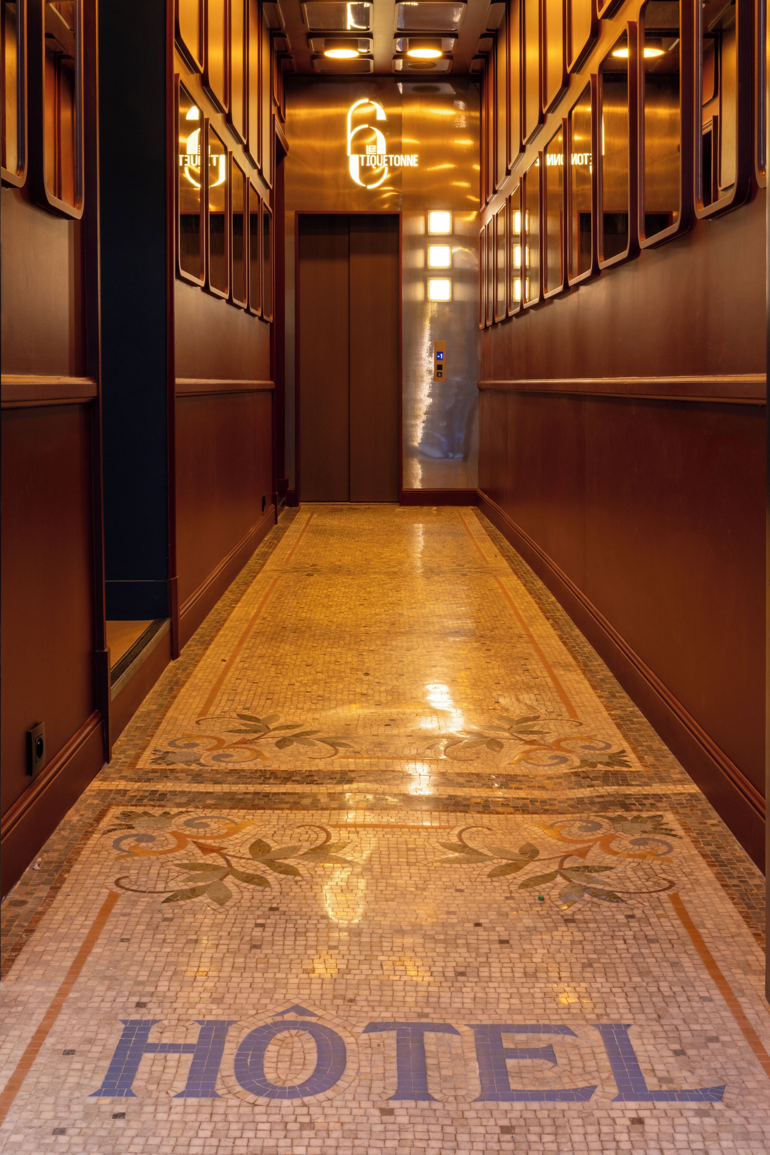 A hotel corridor with a polished floor, a 'HOTEL' sign, and a '6' illuminated sign.