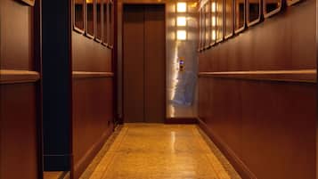 A hotel corridor with a polished floor, a 'HOTEL' sign, and a '6' illuminated sign.
