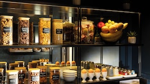 A display of food items in glass jars and bowls, including granola, chocolate chips, and various fruits.