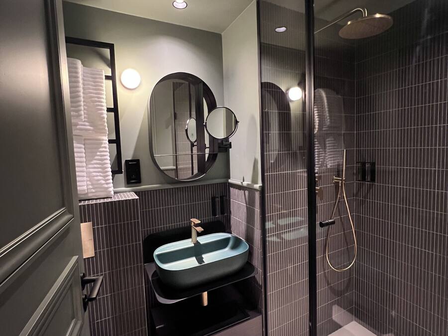Un baño moderno con lavamanos, espejo y ducha.