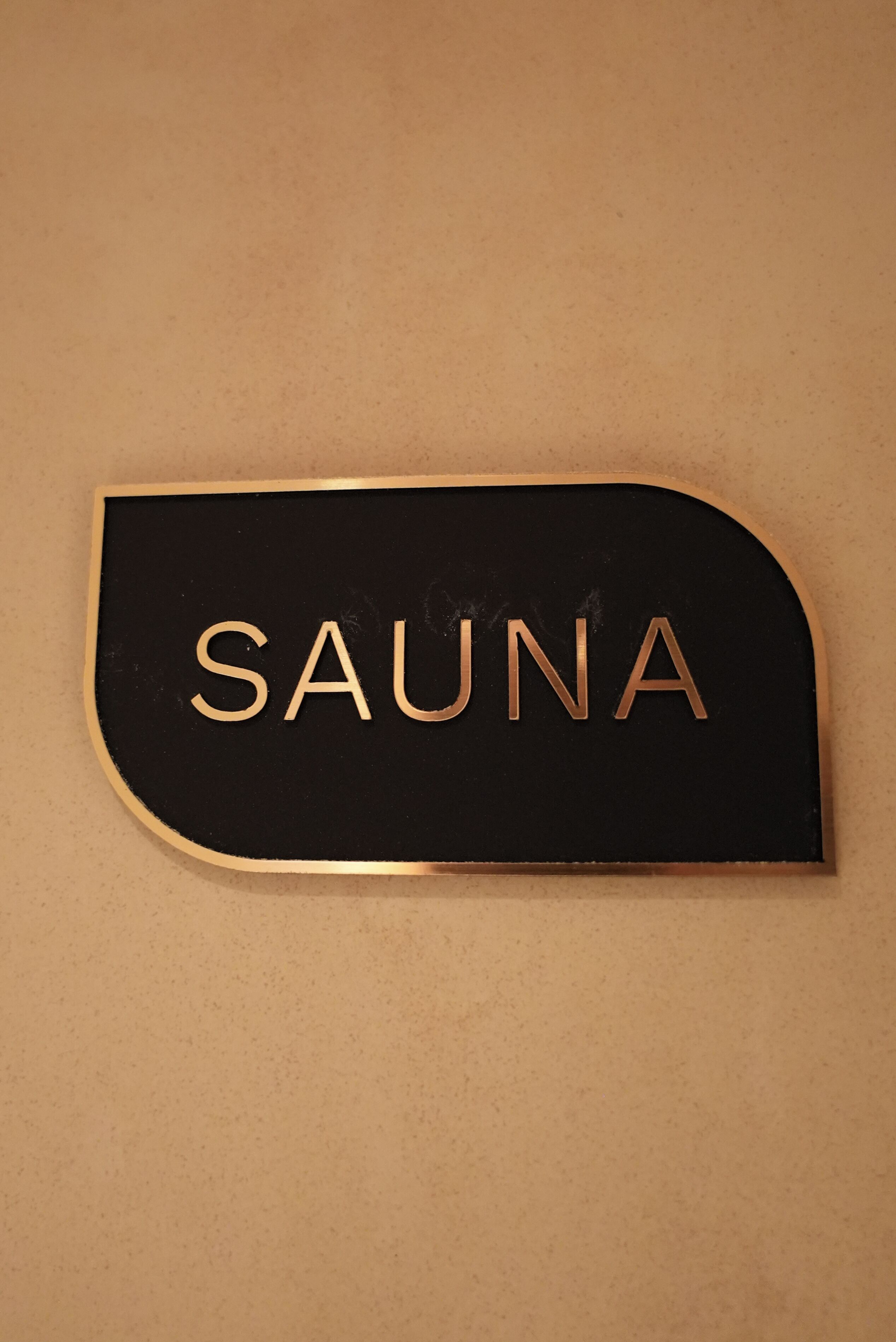 Un letrero negro con la palabra 'SAUNA' en letras doradas.