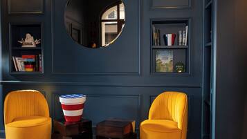 A room with two yellow chairs, a mirror, a bookshelf, and a small American flag decoration.