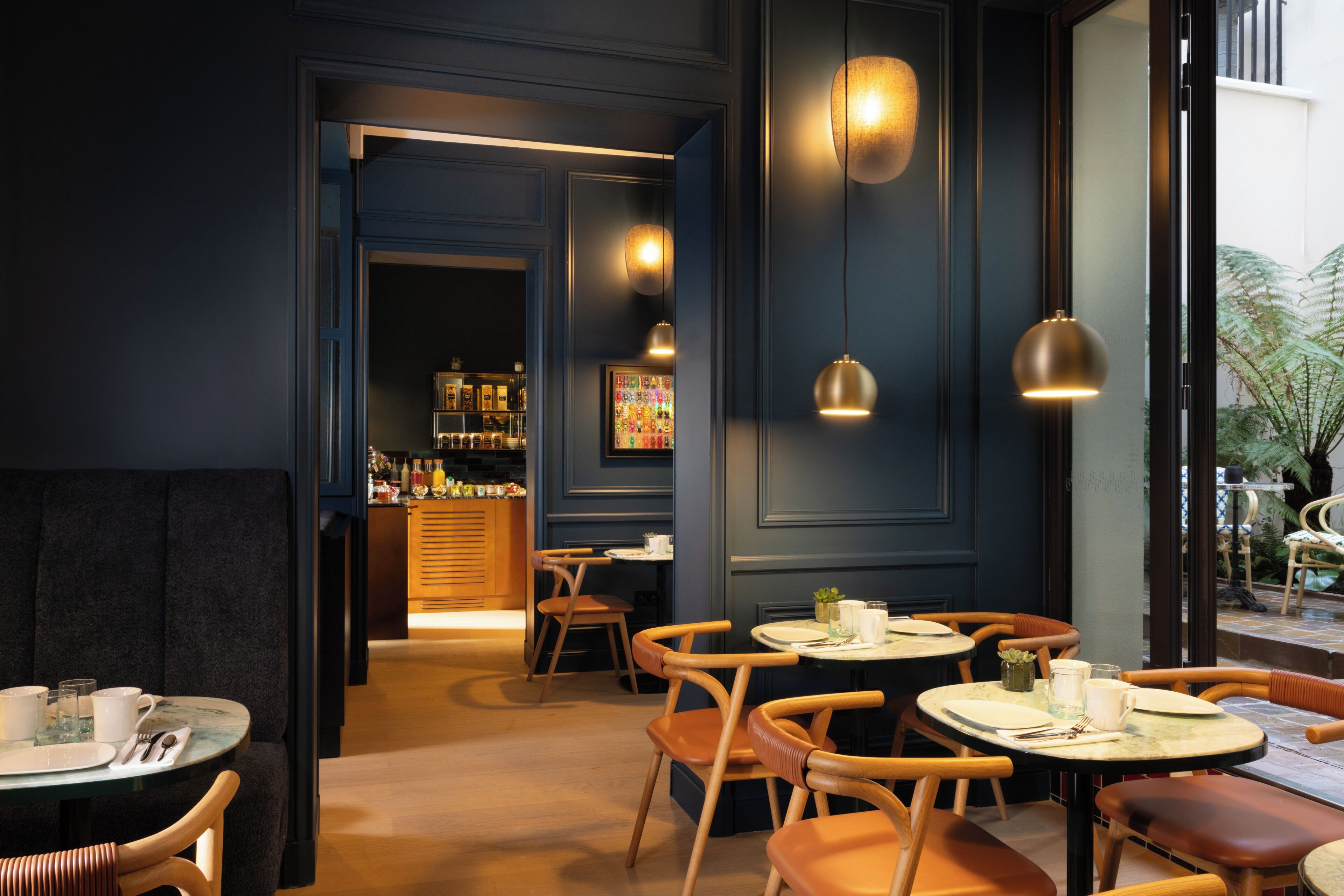 A restaurant with round tables and chairs, a bar area, and pendant lighting.