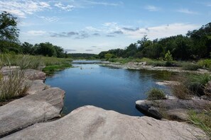 A calm river with surrounding greenery and large rocks. - Hudson’s Hideaway (Johnson City)