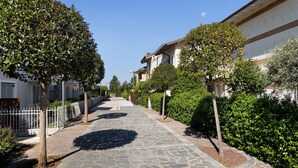 A paved pathway flanked by trees and a white fence, leading to a building with a sloped roof. - Apartment "Betty's House" with Pool, Wi-Fi, and Air Conditioning (Cavalcaselle)