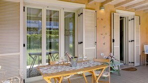 A dining area with a table set for four, a bottle of champagne, and a view of a balcony with a railing. - Apartment "Betty's House" with Pool, Wi-Fi, and Air Conditioning (Cavalcaselle)