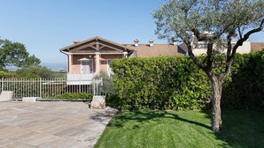 A house with a stone patio, a white fence, and a tree in the foreground. - Apartment "Betty's House" with Pool, Wi-Fi, and Air Conditioning (Cavalcaselle)