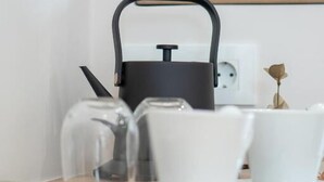 A kitchen counter with a coffee maker, a glass, and a white mug. - Zante Apts (Laganas)