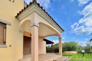 Un bâtiment doté d’une entrée couverte, d’une porte en bois fermée et d’un patio carrelé.