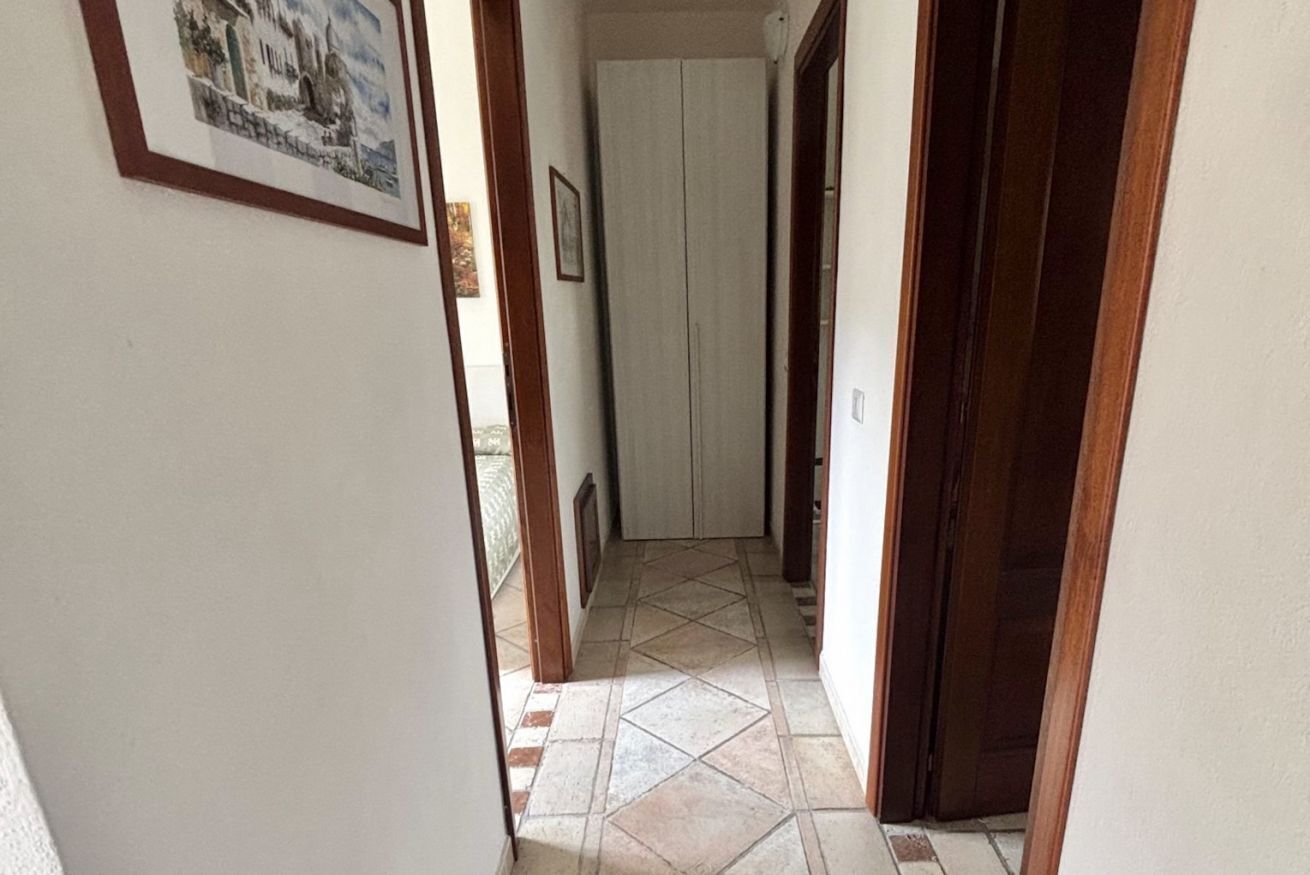 A hallway with a tiled floor, a door, and a framed picture on the wall.