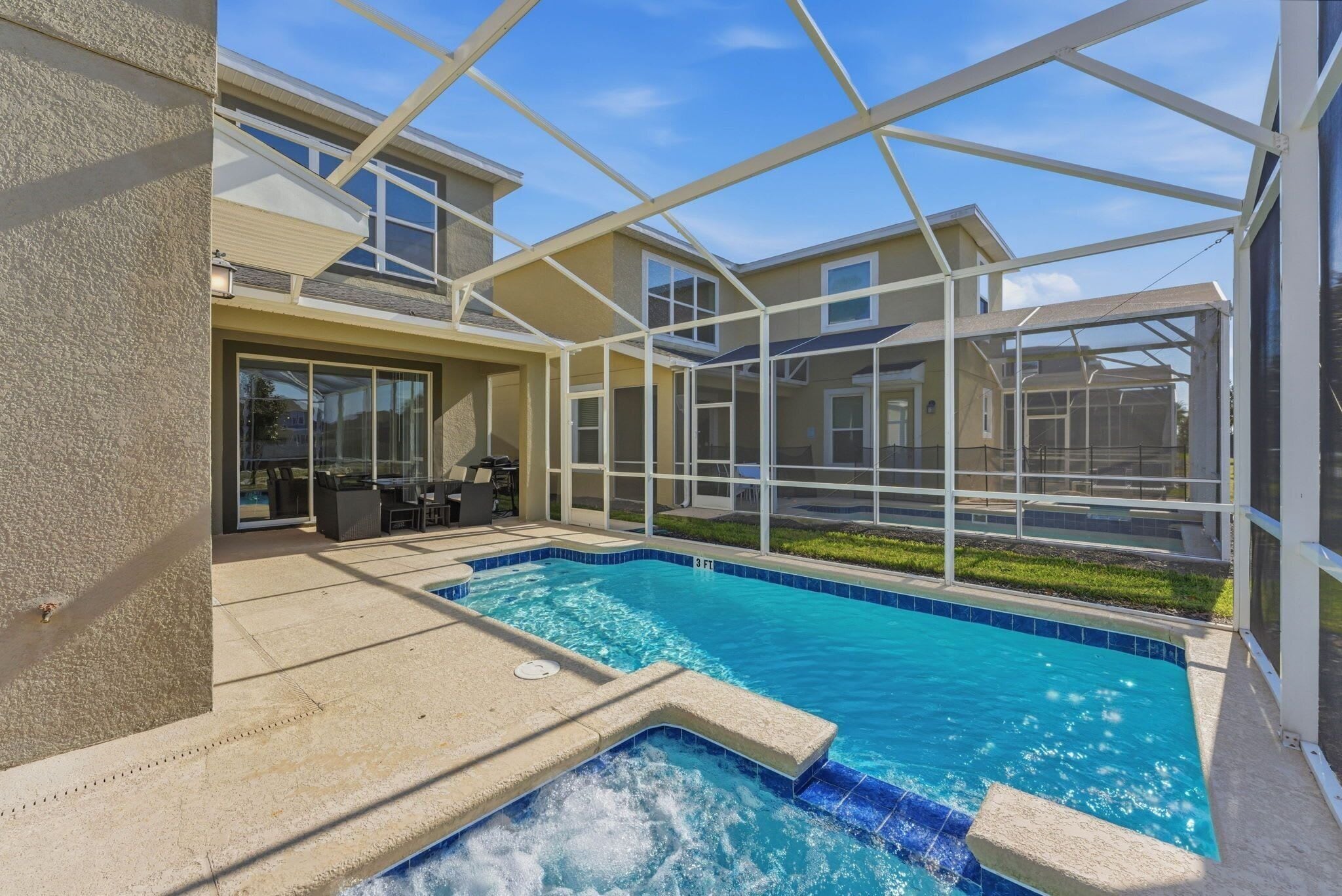 Ein Swimmingpool mit Glasumrandung, eine Terrasse und Blick auf umliegende Häuser.