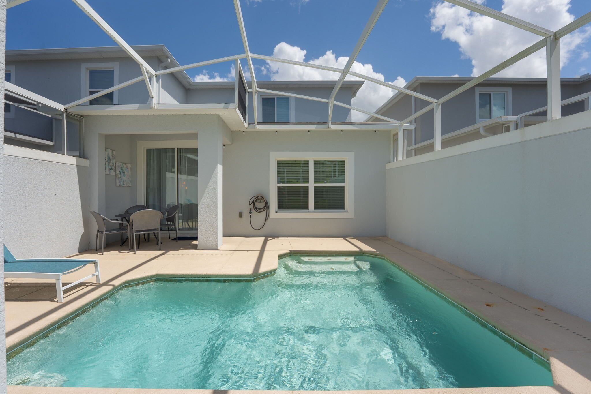 A swimming pool with a covered patio area, a window, and a door leading to an outdoor seating area.