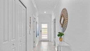 A bright hallway with white doors, a large decorative mirror, and a potted plant. - 5BR Townhome w/ Pool at Champions Gate (Kissimmee)