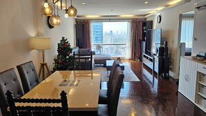 Ein modernes Wohnzimmer mit Essbereich, Weihnachtsbaum und Blick auf die Stadt.