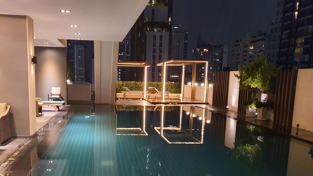 Ein moderner, überdachter Pool mit klarem Wasser, umgeben von Liegestühlen und einem gut beleuchteten Deck.