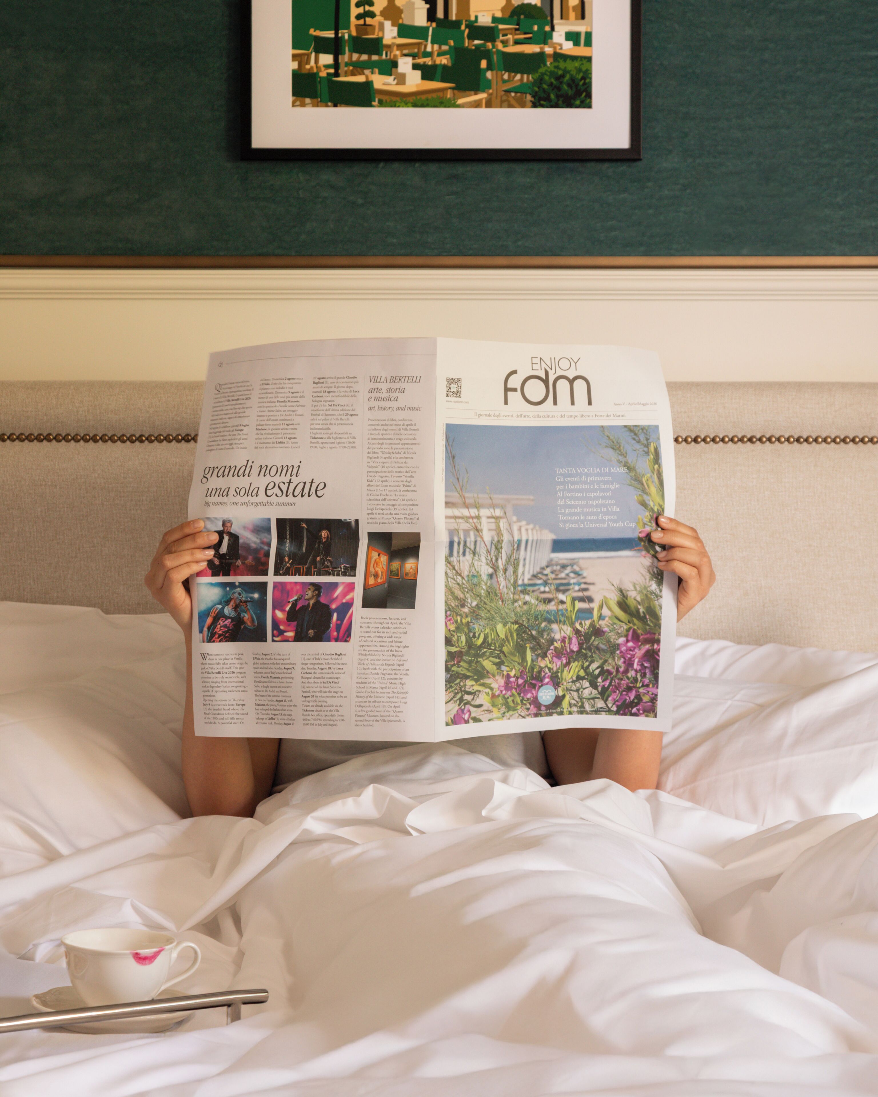 Una persona sdraiata su un letto che legge una rivista.