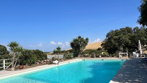 Una piscina rettangolare con acqua cristallina e chiara, circondata da un solarium piastrellato.
