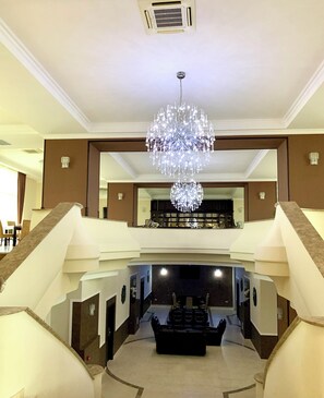 A grand lobby with a large chandelier, a staircase, and a seating area. - Albert Hotel & Restaurant (Ploiești)