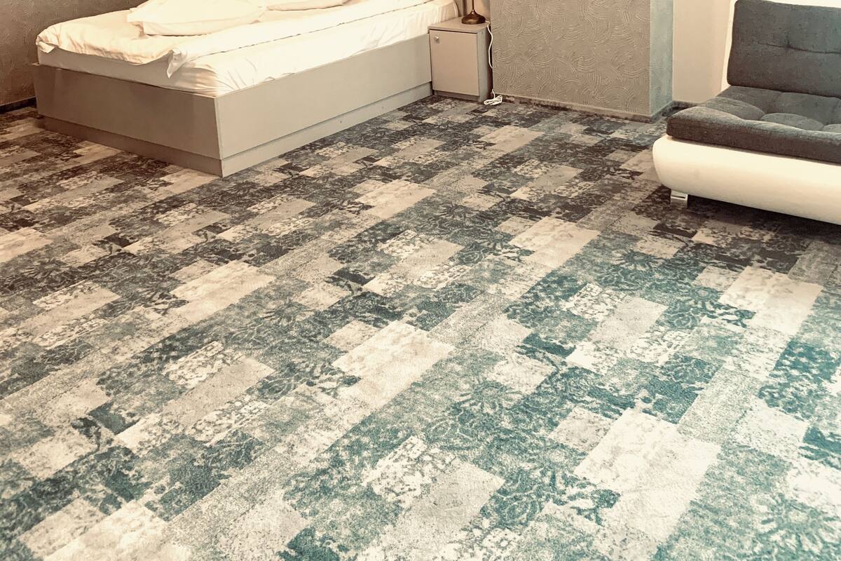 Un dormitorio con cama, mesita de noche, lámpara y una silla.