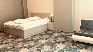 A bedroom with a bed, bedside table, lamp, and a chair.