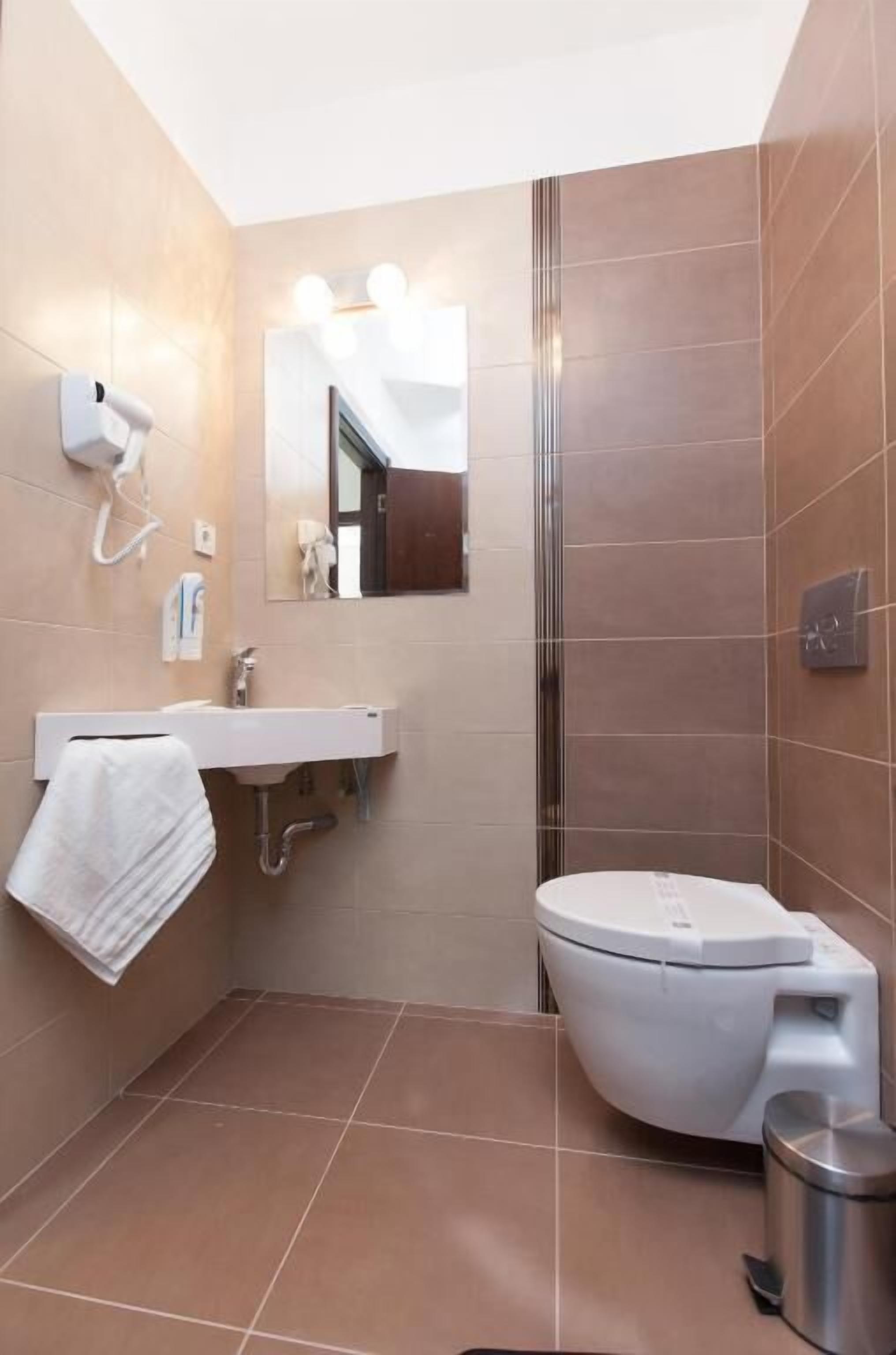 A modern bathroom with a white sink, mirror, and toilet.