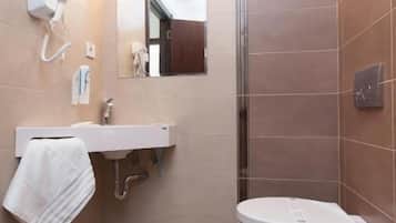A modern bathroom with a white sink, mirror, and toilet.