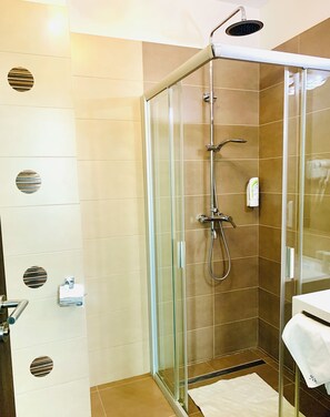 A glass-enclosed shower stall with a handheld showerhead and a wall-mounted faucet. - Albert Hotel & Restaurant (Ploiești)