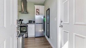 A compact kitchen with a built-in oven, microwave, and refrigerator, a stainless steel range hood, and a door with a 'DO NOT ENTER' sign. - 1bd/1ba Sunnyvale Suite w/ Private Fenced Patio (Sunnyvale)