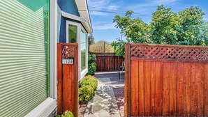 A residential property with a green exterior, a wooden gate, and a paved pathway leading to a wooden deck. - 1bd/1ba Sunnyvale Suite w/ Private Fenced Patio (Sunnyvale)