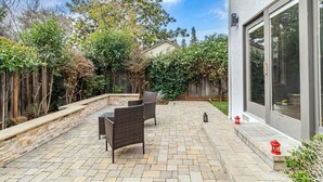 Eine Terrasse mit Steinboden, zwei Korbstühlen und einem kleinen Tisch.