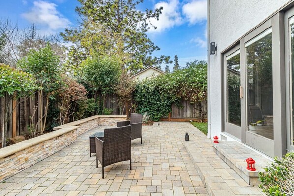 A patio with a stone floor, two wicker chairs, and a small table.