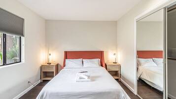 Une chambre d’hôtel avec un grand lit, deux tables de chevet, une fenêtre et un miroir.