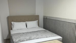 Ett sovrum med en säng, två kuddar, ett sängbord och en bänk.