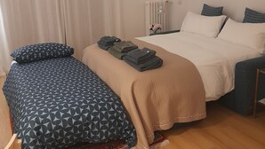 Une chambre à coucher avec un lit, un bureau, une chaise, un radiateur et une fenêtre avec des rideaux.