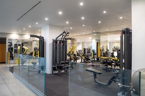 Een moderne sportschool met diverse fitnessapparaten, glazen wanden en een schoon, goed verlicht interieur.
