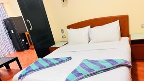 A neatly made bed with white linens and striped towels, a wooden headboard, and a small bedside table. - Porto Golf Marina Apartments (El Alamein)