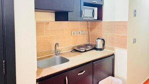 A compact kitchen with a microwave, kettle, and a sink. - Porto Golf Marina Apartments (El Alamein)